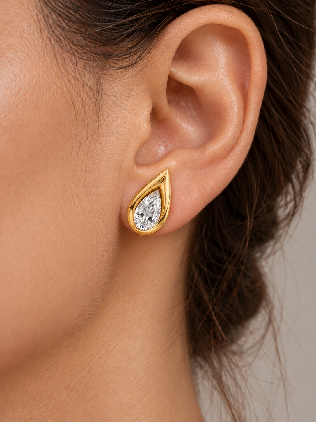Pear-shaped diamond earring in 14k yellow gold shown on an ear
